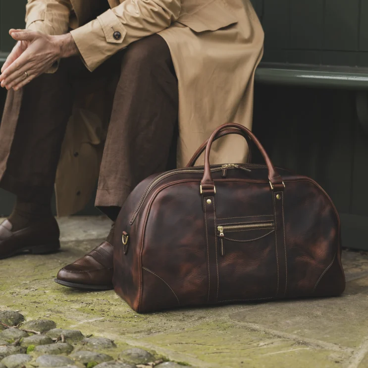 Man sat down with The Stamford bag in tobacco on floor