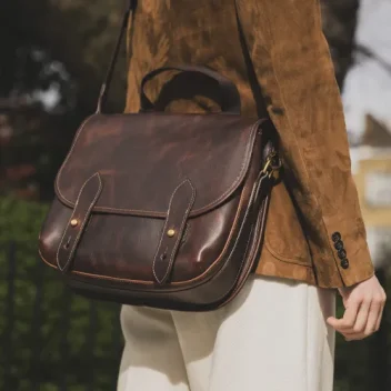 A male model wears The Clifton Messenger Bag in Badalassi – Wax Tobacco